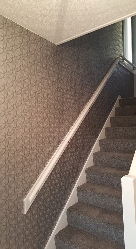 Patterned wallpaper beside a staircase and white handrail